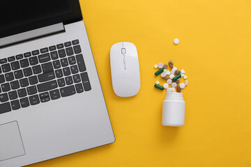 Laptop with bottle of pills on yellow background. Top view. Flat lay