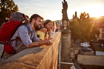 Young man and woman on bridge at Prague  on journey at sunset.