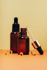 Face serum and vitamin capsules on the trendy orange background. Collagen, hyaluronic acid for skin...