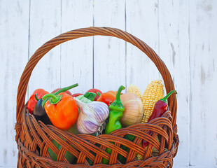 Fototapeta na wymiar wicker basket filled with vegetables on a background of white wooden boards. ecological healthy food concept.