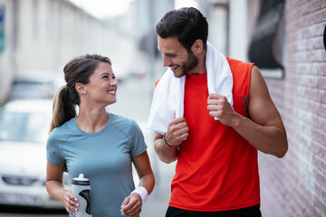 Happy couple is having a rest after jogging in the city. Boyfriend and girlfriend enjoying in the morning.