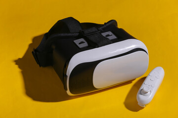 Virtual reality headset with joystick on yellow background with shadow. Modern gadgets