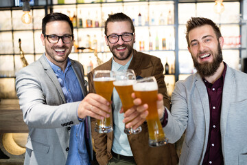 Young businessmen are drinking beer, talking and smiling while resting at the pub