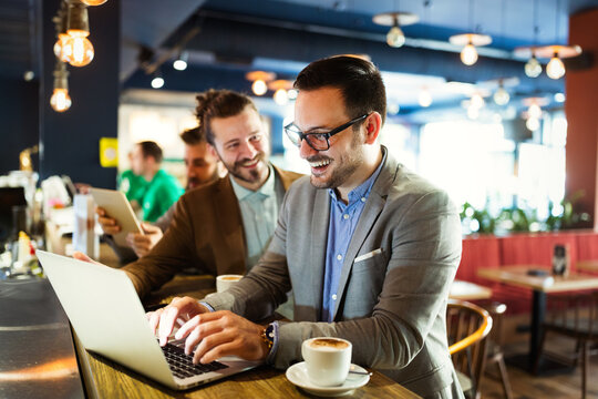 Group of attractive young business men colleagues working together in cafe