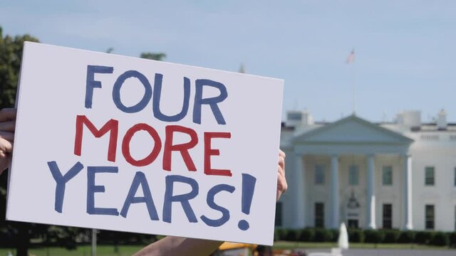 WASHINGTON - Circa August, 2020 - A man holds a handmade FOUR MORE YEARS! election protest sign in front of the White House on a sunny summer day.  	