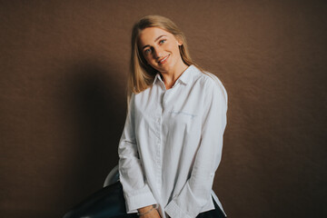 An attractive caucasian blonde female in a white shirt posing on a brown background
