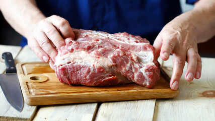 Selective focus. Raw meat in the hands of the chef on a wooden board. Cooking meat.