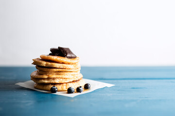 Minimal looking piled pancakes with blueberries over blue wooden vintage backdrop with copy space