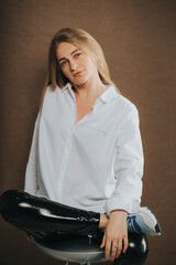 An attractive caucasian blonde female in a white shirt posing on a brown background
