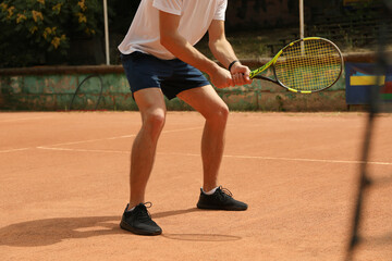 Fototapeta na wymiar Young man playing tennis on clay court