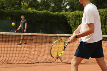 Two men playing tennis on clay court