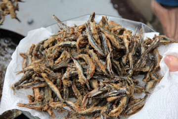 Anchovies are fried in vegetable oil in a pan.