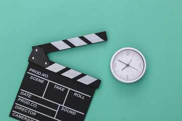 Movie clapper board and alarm clock on a blue pastel background. Filmmaking, Movie production,...