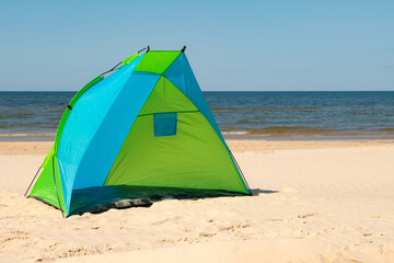 Wind breaker tent on a sandy beach by the sea. Nobody. Colorful tent protection from wind and sunburn.