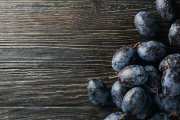 Fresh plums on wooden background, space for text