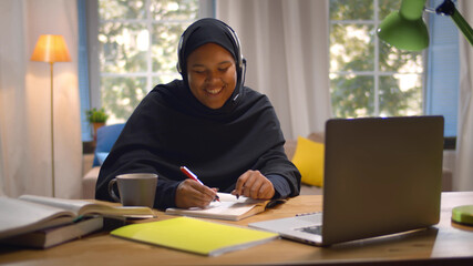 Fototapeta premium Happy Arabic Girl In Headscarf And Headset Studying With Laptop At Home