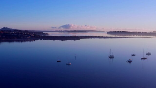 Yachts Floating On The Water As The Sunshine Reflects On A Calm Beach In Auckland, New Zealand. - Aerial Shot