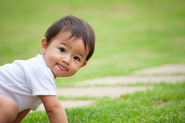 .Portrait of 1 year old Asian-looking girl. Funny scene, Showing the tongue. Outdoor scene. Copy space