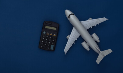 Passenger plane figurine and calculator on classic blue background. Calculation of the cost of air flight. Color 2020. Top view.