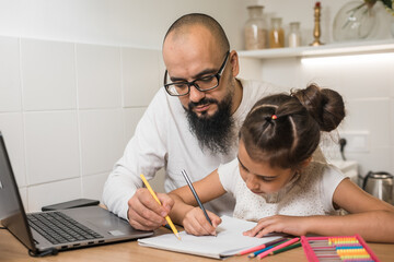 Home school concept,father teach daughter  children doing school homework and his use laptop make overtime in work table in home at night time.
