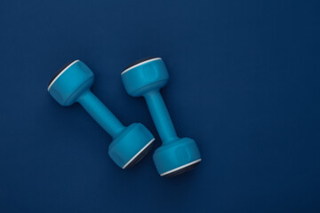 Dumbbells on classic blue background. Healthy lifestyle, fitness training. Color 2020. Top view