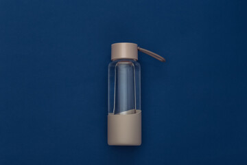 Water bottle on classic blue background. Healthy lifestyle, fitness training. Color 2020. Top view