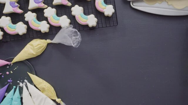 Step by step. Flat lay. Decorating unicorn theme sugar cookies with royal icing on baking sheet.