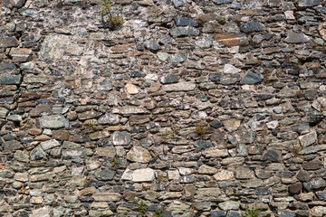 View of a rustic and old schist exterior wall, architectural textures