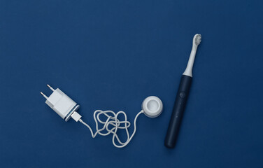 Electro-toothbrush with charger on classic blue background. Color 2020. Top view