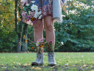 legs in hiking shoes with pretty bouquet of wild flowers