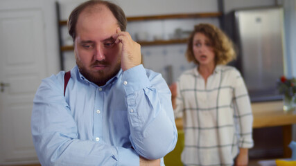 Young wife shouting at desperate overweight husband standing in living room at home