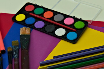 Art supplies for creative minds, paintbrushes, watercolors, pencils and colored cardboard. 