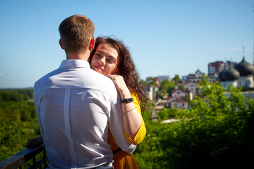 A date between a young girl and a guy on a Sunny summer day. Young beautiful couple on walk in the city. Man and woman at a love meeting with hugs and kisses outdoors