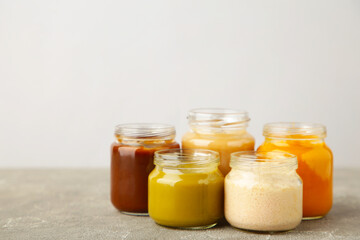 Glass jars with nutrient baby food on light background
