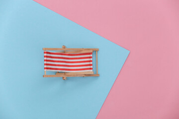 Mini beach chair on a blue-pink pastel background. Top view
