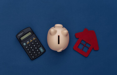 Calculator, piggy bank and house on classic blue background. Color 2020. Top view