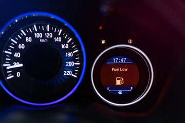 low fuel indicator light on the dashboard. Low fuel guage shown in a car shot