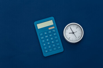 Calculator and clock on classic blue background. Color 2020. Top view