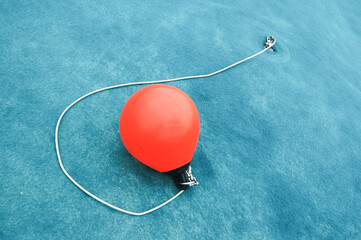 Red drop fender on a light blue background attached to the rope