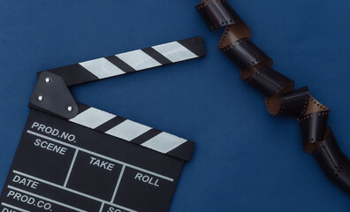 Movie clapper board with film tape on classic blue background. Filmmaking, Movie production,...
