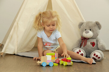 Toddler girl playing with wooden train made from wooden blocks - educational toys for preschool and kindergarten child. 