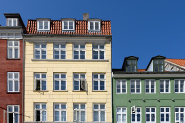 Fototapeta na wymiar Colorful houses in brown, yellow and green of the Nyhaven in Copenhagen Denmark photographed frontally on a sunny day with a bright blue sky.