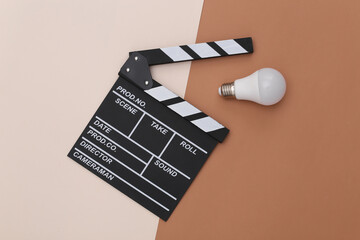 Movie clapper board with light bulb on beige brown background. Filmmaking, Movie production,...