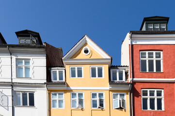 Fototapeta na wymiar Colorful houses in red, yellow and white of the Nyhaven in Copenhagen Denmark photographed frontally on a sunny day with a bright blue sky.