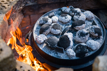 Dutch oven cooking in a campfire with glowing coal on the top