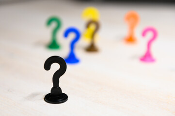 Problem solving and leadership illustrated with play figures in question mark shape in bright colors against white background.