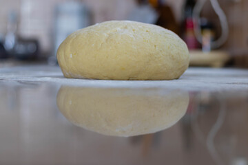 Kneaded homemade fresh dough on marble tabletop with reflection. Dough for making dumplings and gnocchi.