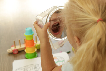 Little toddler girl holding a mirror and making facial expression