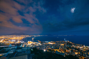Naples, Italy. Skyline Cityscape In Evening Lighting. Tyrrhenian Sea And Landscape With Volcano Mount Vesuvius. City In Night Illuminations