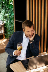 Handsome businessman dressed in the suit drinking wine. Businessman enjoying in the restaurant..